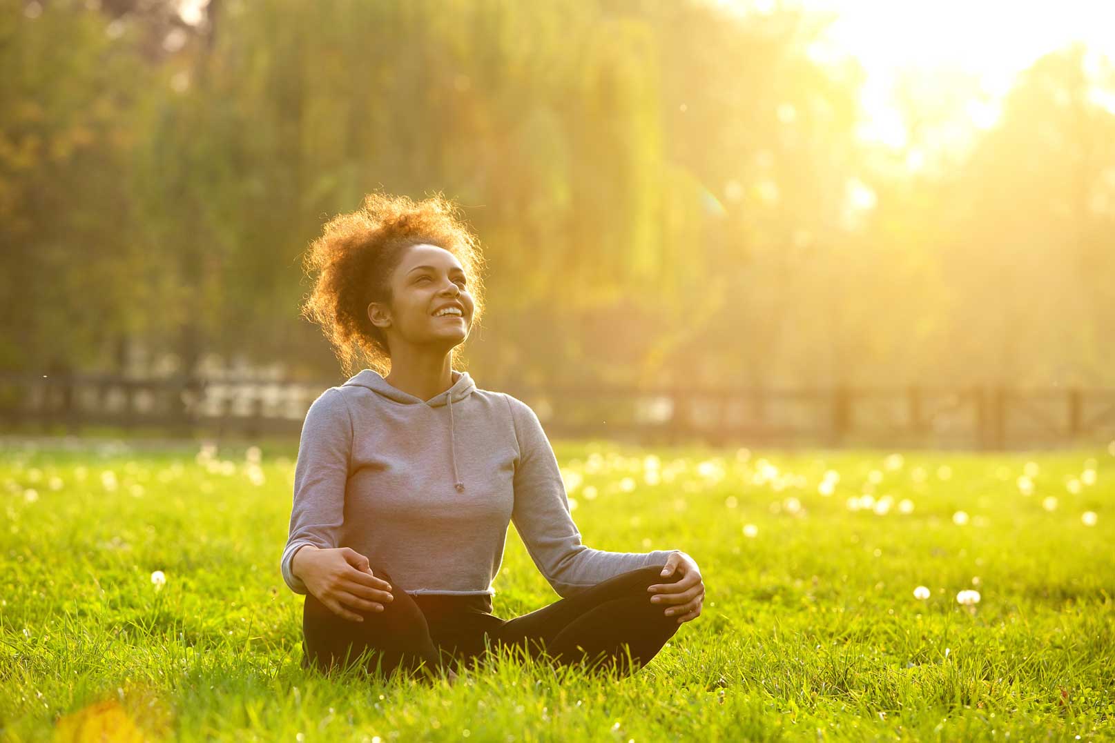 woman seated on grass with sunlight behind her