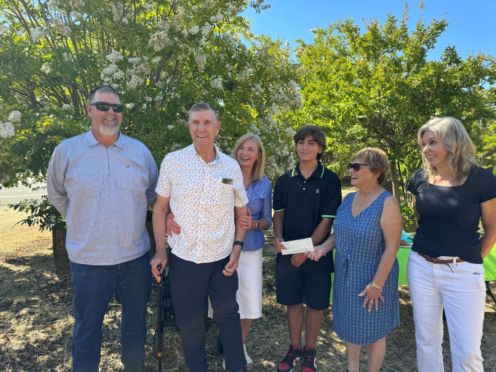 six people smiling standing together infront of trees