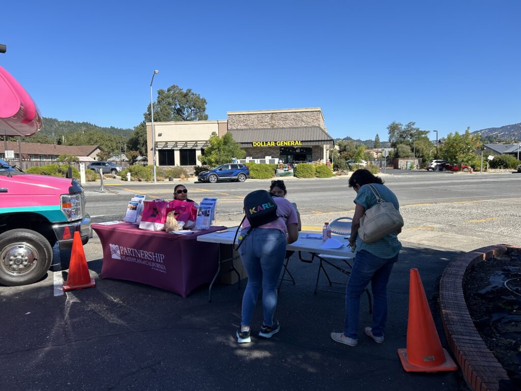 people signing papers on table in a parking lot