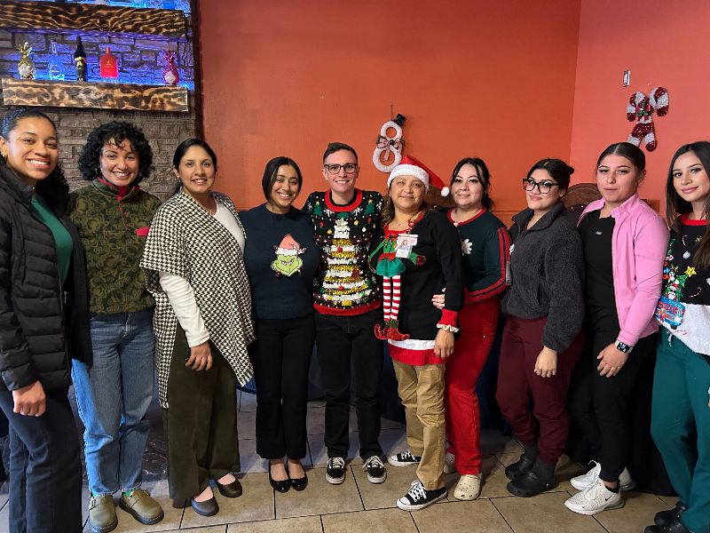 AVH staff gathered together infant of red wall